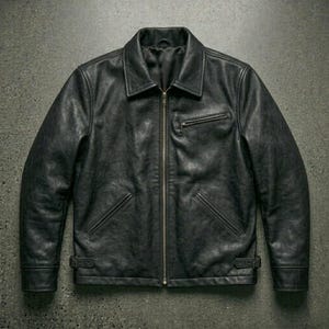 May include: A black leather jacket featuring a full-length front zipper, a pointed collar, and long sleeves. The jacket includes a single zippered chest pocket on the left side, two slanted waist pockets, and adjustable side tabs with buckles at the hem.