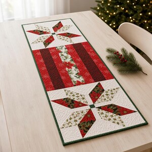 May include: A rectangular quilted table runner featuring two large star-shaped patterns at the ends with white, red, and green poinsettia floral prints. The center section consists of vertical red and dark red stripes with a central floral panel.