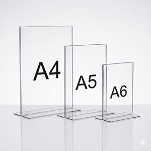 Peut inclure: Trois porte-affiches verticaux en acrylique transparent disposés par taille décroissante. Chaque support présente une base plate et un cadre transparent. Les porte-affiches portent l'inscription noire A4, A5 et A6 pour indiquer leur format.