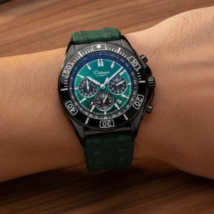 Może przedstawiać: Czarny zegarek chronograf z żywym zielonym cyferblatem, wyposażony w trzy mniejsze tarcze, okienko datownika oraz skalę tachymetru na pierścieniu. Zegarek posiada teksturowany ciemnozielony pasek silikonowy oraz srebrne wskazówki i indeksy.