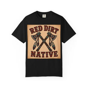 May include: A black short-sleeve t-shirt featuring a square graphic on the chest. The graphic displays the text RED DIRT NATIVE in red and black letters, with two crossed tomahawks decorated with colorful beadwork patterns and hanging feathers.