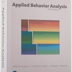 May include: A hardcover textbook titled Applied Behavior Analysis Third Edition by John O. Cooper, Timothy E. Heron, and William L. Heward. The white cover features a central square graphic with a horizontal rainbow gradient and a grid pattern.