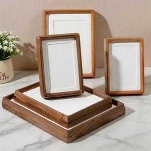 May include: A collection of rectangular wooden picture frames with white matting. The set includes two upright frames and two flat frames stacked horizontally. The frames feature a natural brown wood grain finish and clean, simple edges.