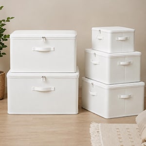 May include: A set of five rectangular white storage boxes of varying sizes, each featuring a zippered lid and a single handle on the front. The boxes are arranged in two stacks, with smooth surfaces and clean, structured edges for organization.