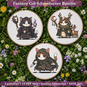 May include: Three circular wooden embroidery hoops containing cross-stitch patterns of fantasy cats. The top left cat wears a dark robe with a skull staff. The top right cat wears a green cloak with antlers. The bottom cat wears a green hood and holds a dagger.