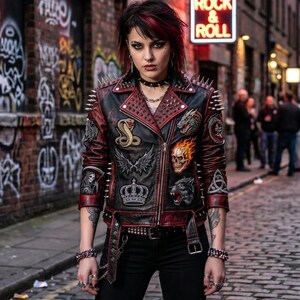 May include: A black and dark red leather motorcycle jacket featuring silver metal spikes on the shoulders and lapels. The jacket is decorated with various embroidered patches including a cobra, a flaming skull, a crown, and a wolf head.
