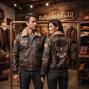 May include: Two brown leather bomber jackets with cream-colored shearling collars. The jackets feature patches of the American and Canadian flags, and the back of one jacket displays an eagle emblem with the text HARE CARTHS embroidered above it.
