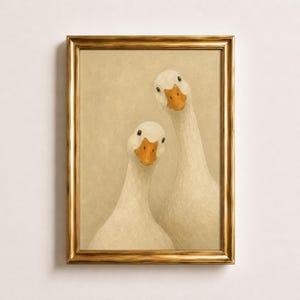 Könnte beinhalten: Ein gerahmter Kunstdruck mit einem Ölgemälde von zwei weißen Gänsen mit orangefarbenen Schnäbeln vor einem strukturierten beigen Hintergrund. Die Gänse sind nah beieinander positioniert, schauen nach vorne und sind in einem goldfarbenen Rahmen.