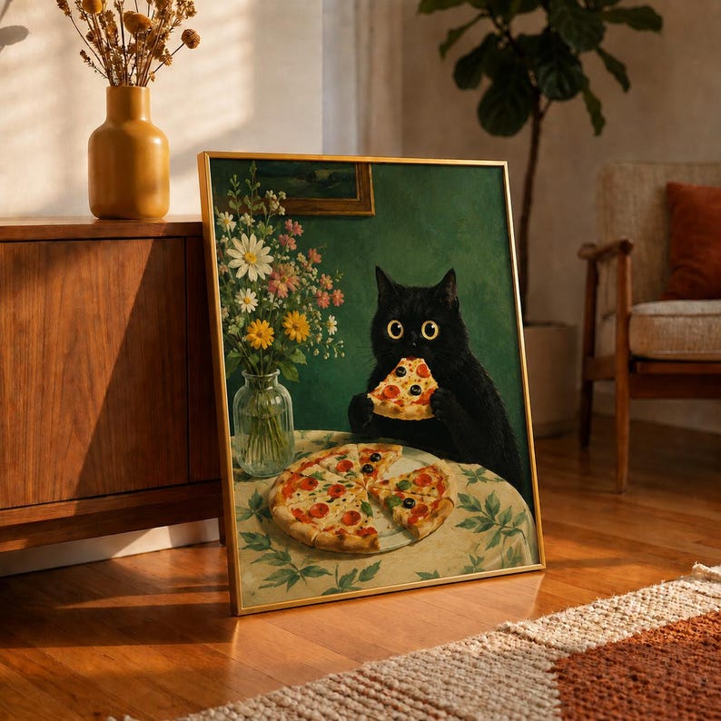 May include: A framed wall art print featuring a black cat with wide yellow eyes eating a slice of pepperoni pizza. A glass vase filled with colorful wildflowers sits on a table covered by a floral tablecloth next to a whole pepperoni pizza.