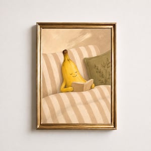 Può includere: Una stampa d'arte incorniciata raffigurante un personaggio a forma di banana gialla con un volto sorridente che legge un libro aperto, seduto su un divano a righe beige e bianche accanto a un cuscino verde con un motivo a foglie.
