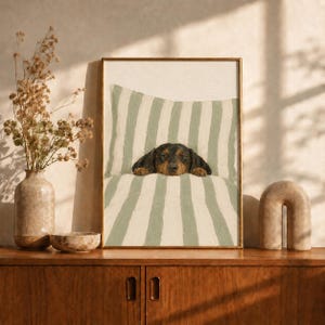 Peut inclure: Une impression d'art encadr&eacute;e repr&eacute;sentant un teckel noir et feu reposant sa t&ecirc;te sur un oreiller &agrave; rayures verticales vert sauge et blanches. Le chien est plac&eacute; au centre du cadre, semblant &ecirc;tre blotti sous une couverture ray&eacute;e assortie.