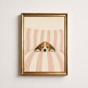 Peut inclure: Une impression d'art encadrée représentant un chiot beagle endormi reposant sur une surface douce à rayures verticales rose clair et blanches. Le chiot a un pelage marron et blanc et est placé au centre, entouré d'un cadre doré.