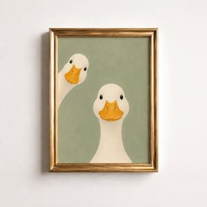 May include: A framed wall art print featuring two white ducks with bright orange beaks set against a solid sage green background. One duck is positioned centrally, while the other peeks in from the left side. The frame is a metallic gold finish.