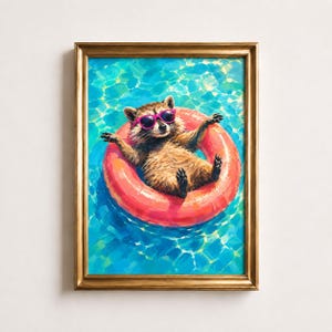 May include: A framed painting of a brown raccoon wearing bright pink sunglasses, floating in a vibrant blue swimming pool inside a large, circular, orange-red inflatable pool ring. The artwork is encased in a metallic gold-colored frame.
