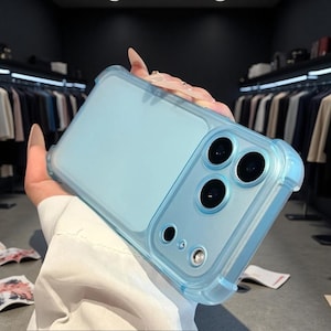 May include: A light blue translucent smartphone case with a smooth matte finish. The case features a rectangular camera cutout area with three circular lens openings, a smaller circular sensor opening, and a small circular flash opening.
