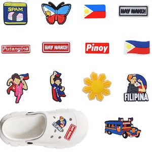 Può includere: Una collezione di ciondoli in gomma colorata per scarpe con disegni a tema filippino, tra cui un Spam musubi, una farfalla, la bandiera filippina, un sole giallo, un jeepney e personaggi con scritte come "HAY NAKU!", "Putangina", "Pinoy" e "FILIPINA".