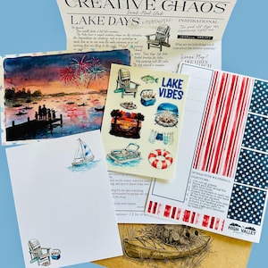 Puede incluir: Un set de papeler&iacute;a que incluye un bolet&iacute;n Creative Chaos, una l&aacute;mina de acuarela de fuegos artificiales sobre un lago, una hoja de pegatinas con motivos lacustres, papel de carta con un velero y una tarjeta interactiva roja, blanca y azul.