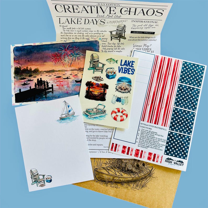 Puede incluir: Un set de papeler&iacute;a que incluye un bolet&iacute;n Creative Chaos, una l&aacute;mina de acuarela de fuegos artificiales sobre un lago, una hoja de pegatinas con motivos lacustres, papel de carta con un velero y una tarjeta interactiva roja, blanca y azul.