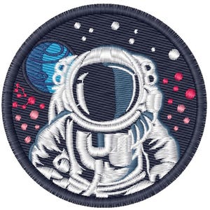 May include: A circular embroidered patch featuring a white astronaut suit against a dark navy blue background. The design includes a blue planet, small white stars, and clusters of pink circular elements arranged in a space-themed composition.