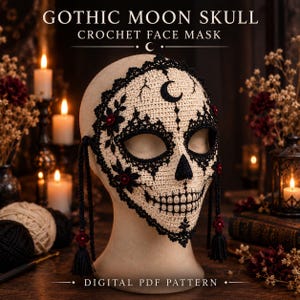 May include: A beige crochet face mask featuring black lace-like trim, a crescent moon symbol on the forehead, and a skull design. The mask includes black stitched eye sockets, a triangular nose, and a toothy grin, with black tassels and red beads.