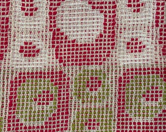 May include: A woven textile fabric featuring a grid pattern of cream, bright red, and olive green threads. The design consists of repeating rectangular and circular motifs created by the interlacing of colored yarns in a textured, open-weave structure.
