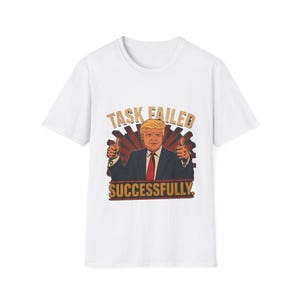 Puede incluir: Una camiseta blanca de manga corta con un estampado gráfico de una persona con traje azul y corbata roja haciendo un gesto de pulgar hacia arriba con ambas manos. El texto "TASK FAILED" aparece arriba y "SUCCESSFULLY." aparece debajo.