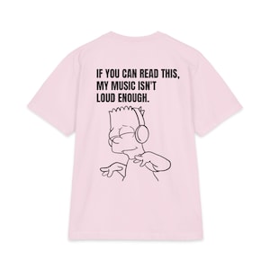 Op de afbeelding: Een lichtroze T-shirt met korte mouwen en een zwarte lijntekening van een stripfiguur met een koptelefoon. Boven het figuur staat de tekst: IF YOU CAN READ THIS, MY MUSIC ISN'T LOUD ENOUGH. Het ontwerp staat op de achterkant van het shirt.