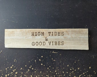 May include: A wooden sign with the text "HIGH TIDES & GOOD VIBES" burned into the surface. The sign is on a dark brown background.
