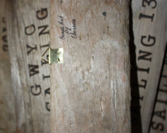 May include: A weathered wooden sign with the text "GWYC SAILING" in black paint. The sign has a metal hook on the top and is labeled "Beagle, Mast 14, Cherisse".