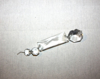 May include: A crystal chandelier prism with a rectangular shape and two smaller round crystals attached to it.
