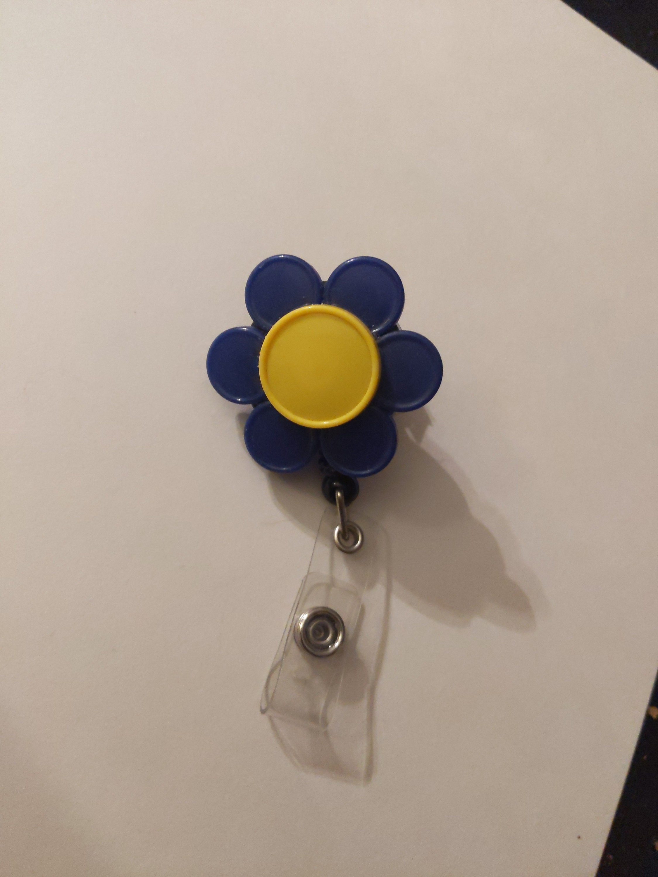 Retractable name badge holder made out of recycled flip off medicine caps.