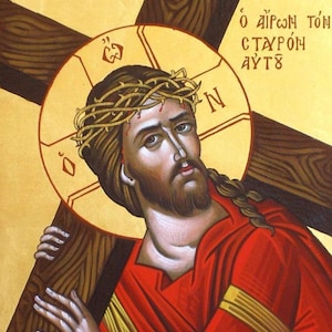 May include: A religious icon painting on a gold background depicting a figure with a crown of thorns carrying a large wooden cross. The figure wears a red robe and has a golden halo. Greek text is visible in the upper corners of the artwork.