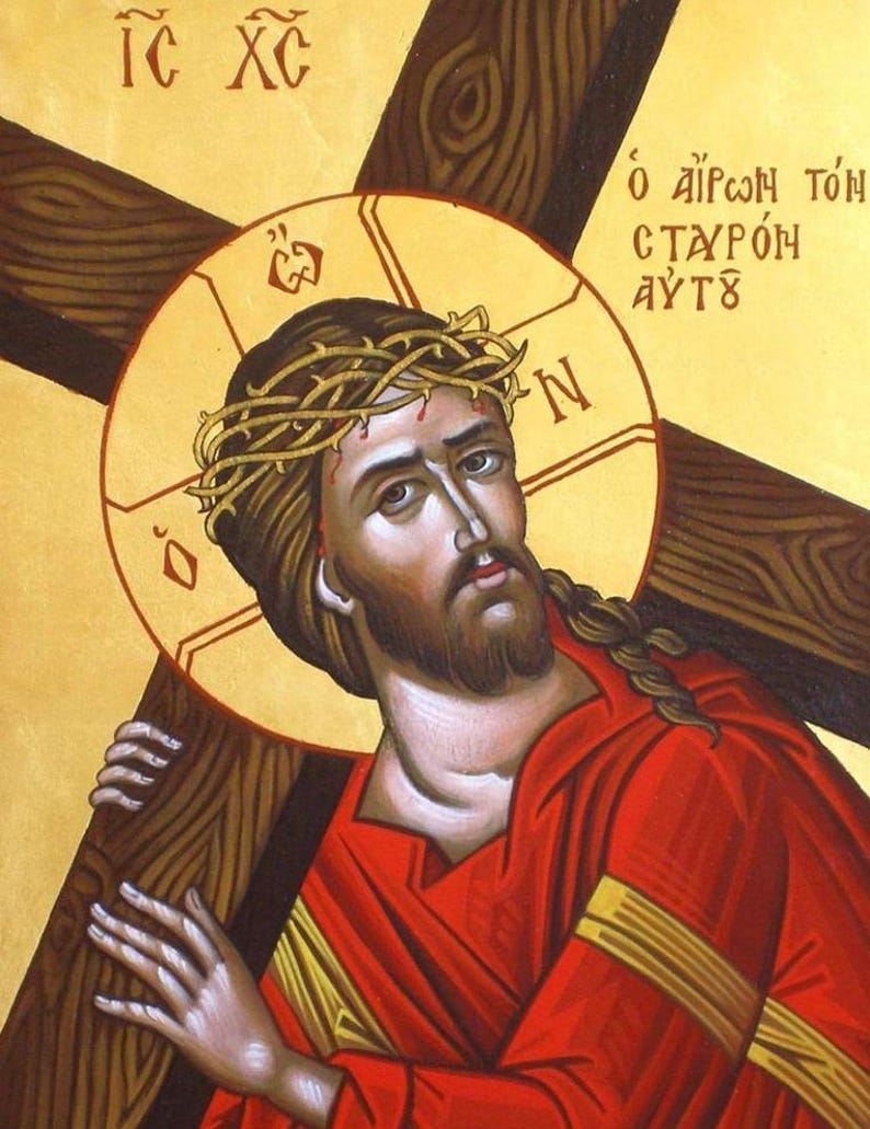 May include: A religious icon painting on a gold background depicting a figure with a crown of thorns carrying a large wooden cross. The figure wears a red robe and has a golden halo. Greek text is visible in the upper corners of the artwork.