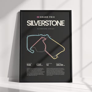 May include: A framed black poster featuring a white map of the Silverstone Grand Prix circuit with colored track segments. The text includes GRAND PRIX, SILVERSTONE, and statistics like 1948, 5.891 km, 52 laps, and 306.198 km in white font.
