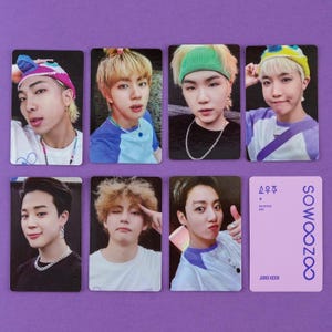 May include: A set of seven rectangular photo cards featuring portraits of seven individuals and one light purple card with the text SOWOOZOO and JUNG KOOK. The portraits show various individuals wearing colourful hats, shirts, and silver chain necklaces.