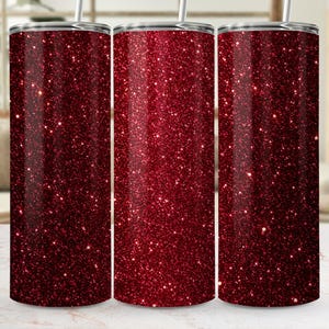 Könnte beinhalten: Drei zylindrische Trinkbecher mit einer tiefroten Glitzerbeschichtung, die die gesamte Oberfläche bedeckt. Jeder Becher ist mit einem silberfarbenen Deckel versehen und enthält einen dünnen, geraden Metallstrohhalm, der aus der Mitte ragt.