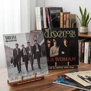 May include: Two wooden vinyl record display stands holding album covers. The left stand holds Nirvana's 'Nevermind' and features the text 'On Air - Live at the BBC Volume 2' and 'Where Words Fail, Music Speaks'. The right stand holds The Doors' 'L.A. Woman'.