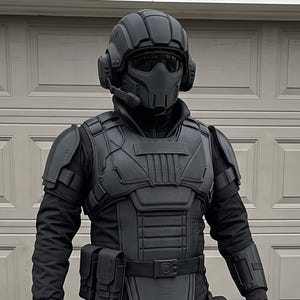 May include: A full-body matte black tactical suit featuring a protective helmet with a face shield, a chest plate with integrated shoulder guards, arm bracers, a utility belt with attached pouches, leg armor, and matching black boots.
