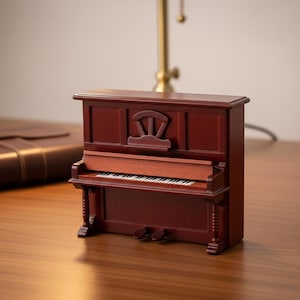 May include: A miniature upright piano crafted from dark reddish-brown wood. The model features a detailed keyboard with black and white keys, a decorative carved panel above the keys, two small pedals at the base, and two fluted front support legs.
