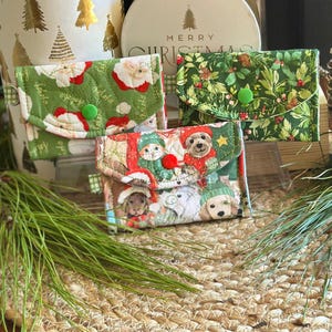 May include: Three quilted fabric pouches with snap closures. One pouch features a green background with Santa Claus figures, one has a green holly and berry print, and the third displays various dogs wearing winter hats and scarves.