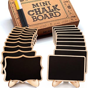 May include: A set of mini chalkboards with black surfaces and light wood frames, including two distinct shapes with removable stands. The product is packaged in a brown cardboard box labelled MINI CHALK BOARD, accompanied by a yellow and white chalk stick.