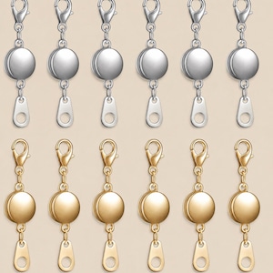 May include: A set of twelve metal zipper pull replacements arranged in two rows. The top row features six silver-toned pulls, and the bottom row features six gold-toned pulls. Each pull consists of a lobster clasp, a circular disc, and a flat tab.