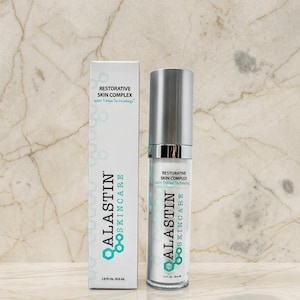Pu&ograve; includere: Una scatola rettangolare bianca e un flacone cilindrico con erogatore a pompa di Alastin Skincare Restorative Skin Complex con TriHex Technology. Entrambi gli articoli presentano testo nero e verde acqua, con un volume di 29,6 ml.