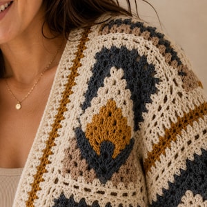 May include: A crochet cardigan featuring a geometric pattern constructed from interconnected squares. The garment displays a color palette of cream, dark charcoal gray, and mustard yellow, showcasing intricate stitch work and textures.