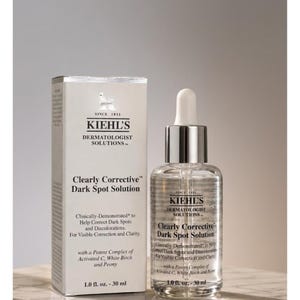 Op de afbeelding: Een witte rechthoekige doos en een doorzichtig glazen druppelflesje van Kiehl's Dermatologist Solutions Clearly Corrective Dark Spot Solution. Beide items bevatten het Kiehl's-logo, zwarte tekst en vermelden een inhoud van 30 ml.