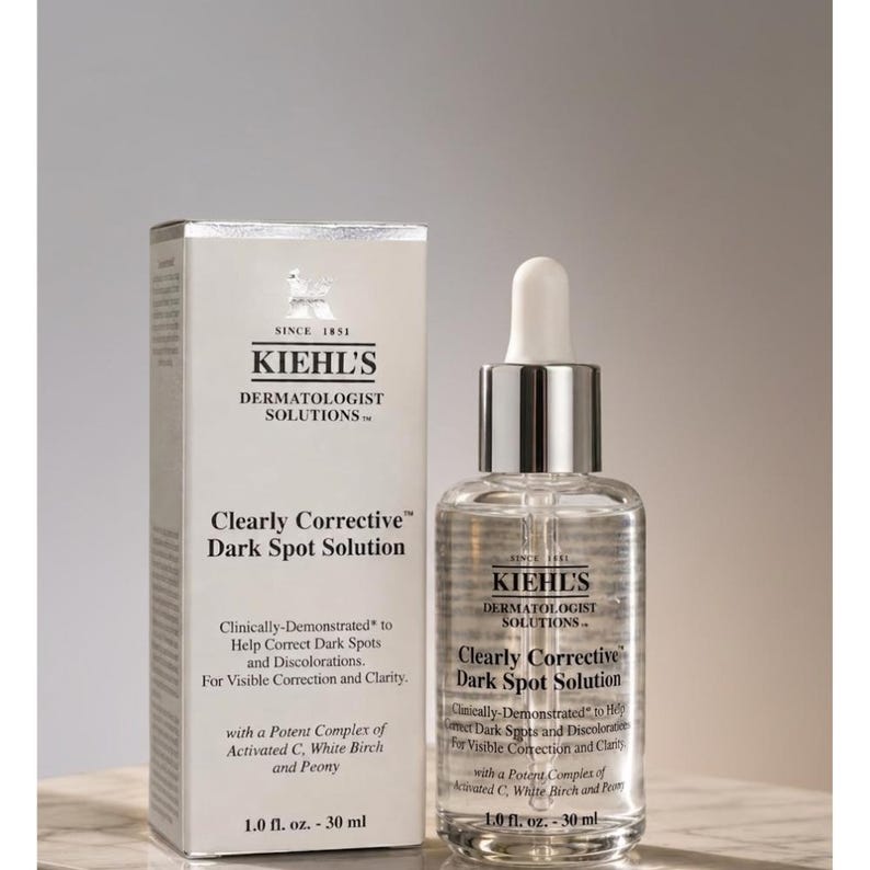 Op de afbeelding: Een witte rechthoekige doos en een doorzichtig glazen druppelflesje van Kiehl's Dermatologist Solutions Clearly Corrective Dark Spot Solution. Beide items bevatten het Kiehl's-logo, zwarte tekst en vermelden een inhoud van 30 ml.