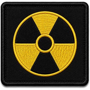 May include: A square-shaped patch featuring a black background with a centred yellow radiation symbol. The design is enclosed within a stitched border, showcasing a high-contrast graphic element with clean, embroidered lines and a textured finish.