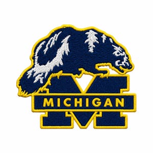 May include: An embroidered patch featuring a dark blue wolverine silhouette with white fur detailing, positioned above a large dark blue letter M. A horizontal dark blue bar across the M contains the yellow text MICHIGAN, all outlined in yellow.