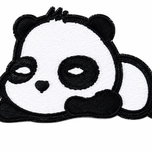 May include: An embroidered patch featuring a stylized, sleeping panda bear. The design is rendered in high-contrast black and white thread, showing the panda lying on its side with closed eyes, rounded ears, and a small nose, finished with a black border.