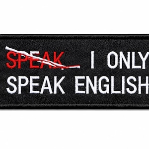 Puede incluir: Un parche rectangular negro bordado con un borde blanco. El texto dice "SPEAK" en rojo con una línea blanca tachada, seguido de "I ONLY" en blanco, y las palabras "SPEAK ENGLISH" en blanco en la segunda línea.